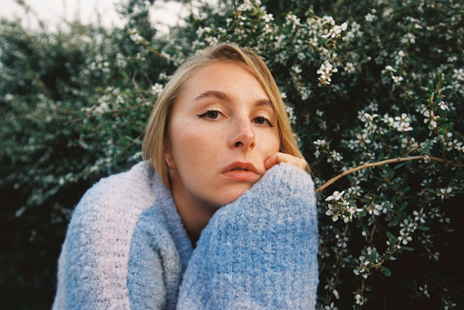 A young woman with blonde hair wearing a sweater.
